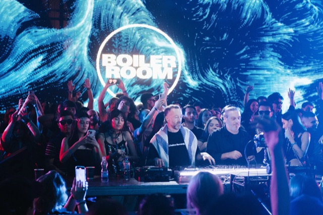 Диджеи за пультом на фоне синей сцены Boiler Room